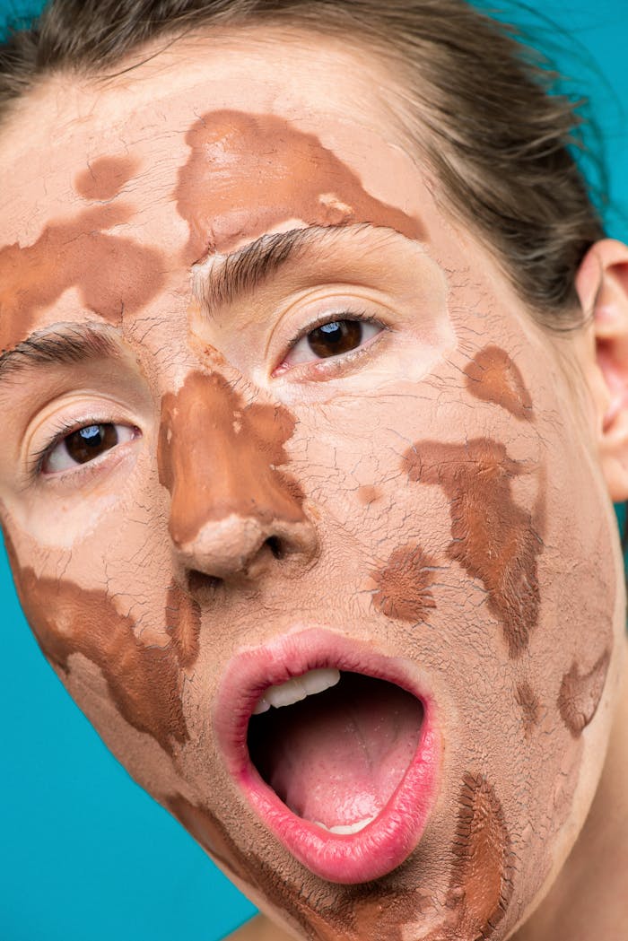 Woman's face with a drying clay mask, showing texture and skin care focus.
